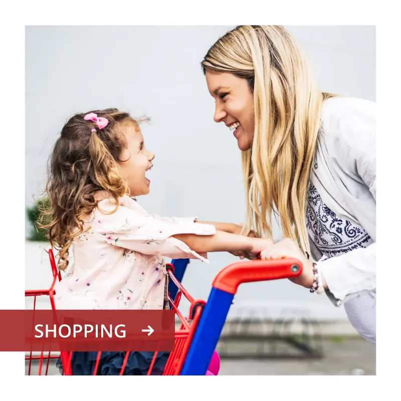 Vacaville-Homepage-Squares-Shopping-min Smiling mother and young daughter play with a toy shopping cart; graphic reads “Shopping.”